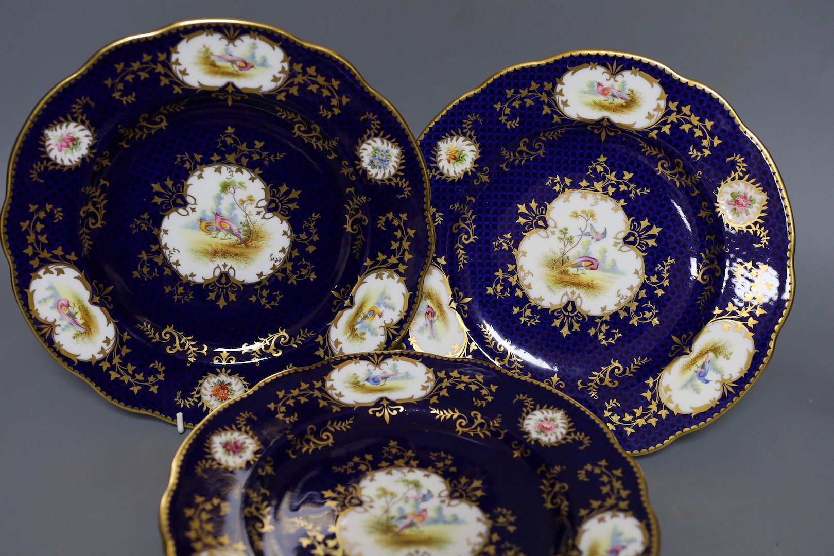 A Late 19th/early 20th century Coalport set of six plates and a square dish, which is signed F Howard, one plate signed P Simpson and four plates initialled PHS for Percy Simpson, Coalport crown England mark and T Goode